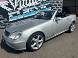 une Mercedes SLK cabriolet argentée garée devant une pancarte « Vintage Fix »