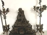 une statue représentant une femme assise sur une table, à côté de trois bougies