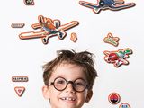 a young boy with glasses standing in front of a wall with stickers on it