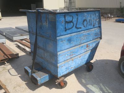 une benne bleue posée sur une palette dans un parking