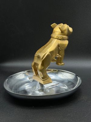 gold dog figurine on a silver plate on a black background