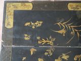 a black and gold box with flowers and leaves on it