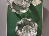two clear glass flowers on a green surface