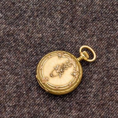 une image représentant une montre de poche en or posée sur un morceau de tissu
