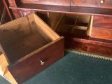 une caisse en bois ouverte, posée par terre à côté d'une commode