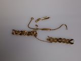 a gold bracelet and a gold chain on a white surface