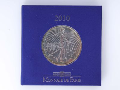 un gros plan sur un livre bleu sur lequel repose une pièce d'argent