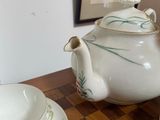 a table with a tea pot and a tea cup and saucer