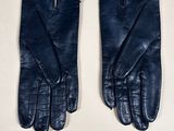 two pairs of black leather gloves on a white surface