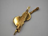 a close up of a gold plated violin brooch
