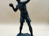 une statue représentant un homme en train de lancer une balle sur une surface blanche
