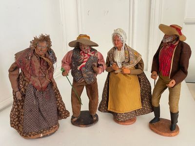 three figurines of people dressed in colonial clothing are posed on a white surface