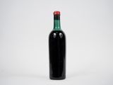 une bouteille noire avec un bouchon rouge posée sur une surface blanche