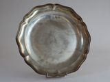 silver plate with scalloped edge on stand on white background
