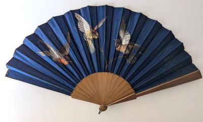 un éventail bleu orné d'oiseaux, accroché au mur