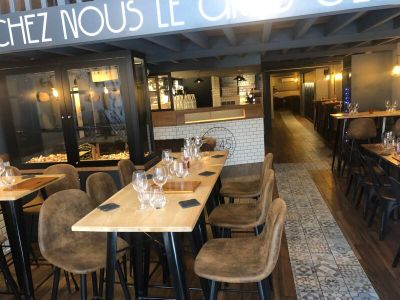 Dans un restaurant, des tables et des chaises sont alignées, avec une enseigne au-dessus.