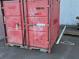 a red container sitting in a parking lot next to a building