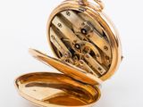 a gold pocket watch inside of it on a white surface