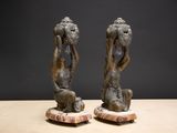 pair of bronze sculptures of a man and a woman sitting on a rock