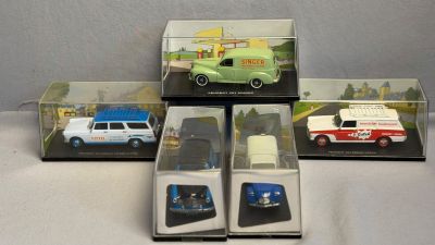 Quatre modèles réduits de voitures différents sont exposés dans une vitrine posée sur une table
