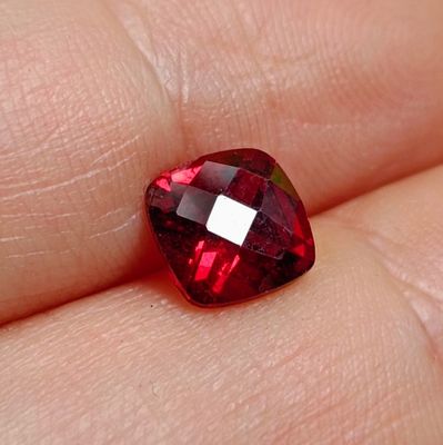 un gros plan sur la main d'une personne tenant une pierre rouge en forme de cœur