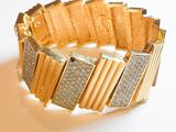 un bracelet en or serti de diamants, posé sur un fond blanc