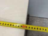 a measuring tape on a piece of wood next to a person ' s feet