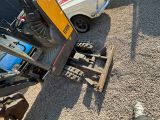 someone standing next to a tractor with a skid steer attached to it