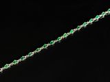 un gros plan d'un bracelet orné de pierres vertes sur fond noir