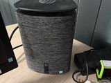 a black speaker sitting on a desk next to a monitor