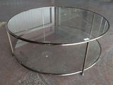 a glass coffee table with a metal base on the floor