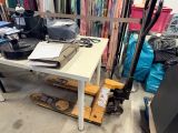 une table blanche sur laquelle est posé un ordinateur portable, au milieu d'une pièce