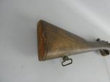 an old wooden gun mounted on a wall with a metal hook