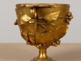 a gold vase with a bird on it on a table