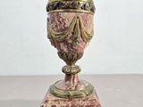 urne antique en marbre rose rehaussée de touches dorées, posée sur un socle en marbre