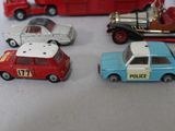 several toy cars are lined up on a table with a red bus in the background