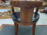 a wooden chair with a black leather seat in a room