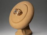 a gold ring sitting on top of a beige hat