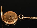 a gold pocket watch on a chain on a black surface