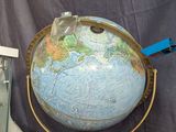 un grand globe terrestre posé sur un socle, avec une vitrine en verre devant
