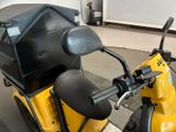 a yellow scooter parked in a garage with a black seat