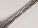 a silver spoon with a handle on a white surface