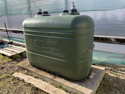 a large green tank sitting on a pallet in a greenhouse