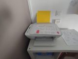 a printer sitting on top of a desk next to a book shelf
