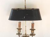 a lamp that is on a table with a painting on the wall behind it