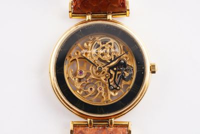 a gold wrist watch with a black face and a brown strap