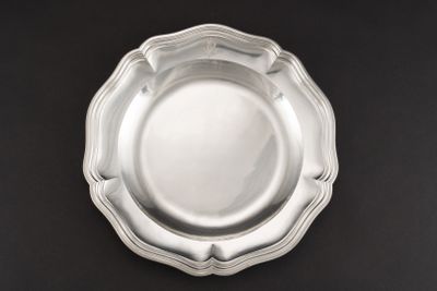 une assiette en argent posée sur une table noire, sur fond noir