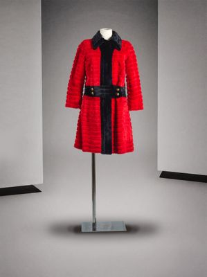 une photo d'un manteau rouge avec une ceinture noire, posé sur un présentoir pour mannequin