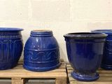 four blue vases sitting on a pallet in front of a white wall