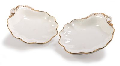 two white and gold shell shaped dishes on a white surface